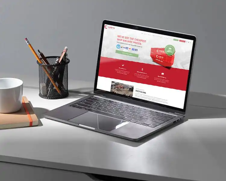 Modern laptop displaying a web design, on a tidy desk with office accessories.